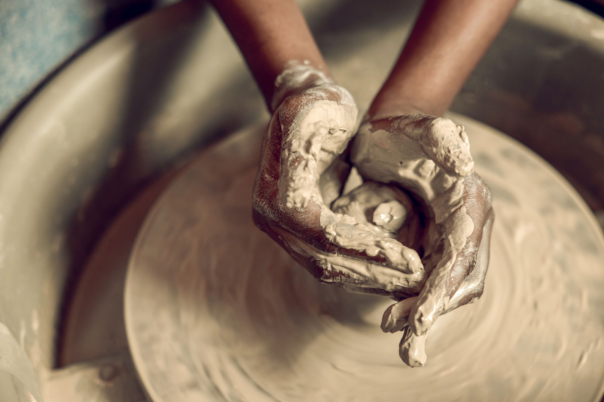 Close up picture of hands working with wet clay and molding its shape